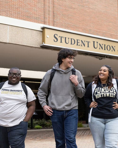 Three students walk together outside of the Student Union Library Building.