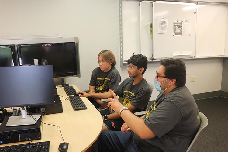 Three students looking at a computer at a PNW Summer Camp