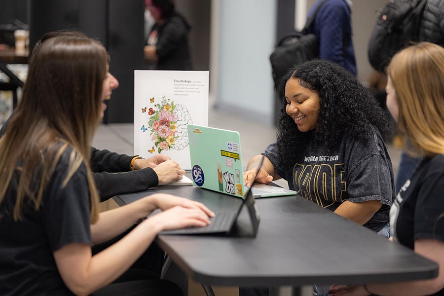 Four PNW students talking to each other while on their laptops