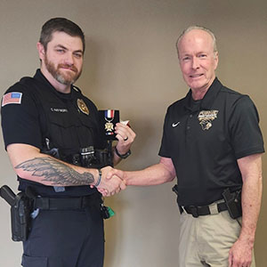 Brian Miller shakes hands with Cody Hayworth and hands Cody an award.