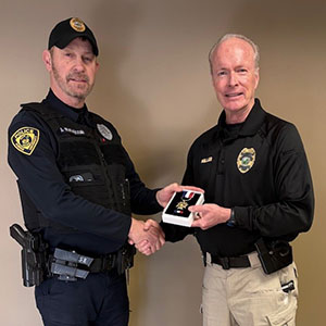 Brian Miller shakes hands with JT Ratajczak and hands JT an award.