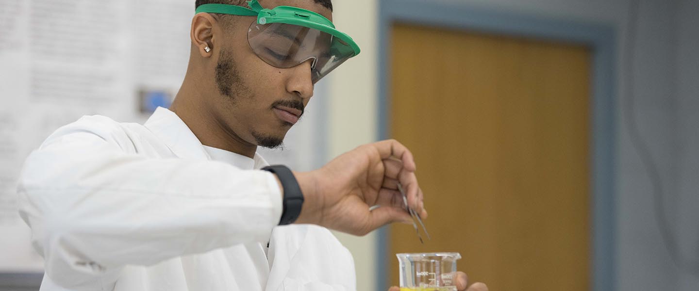 PNW student mixing liquids in a glass flask 1440x600