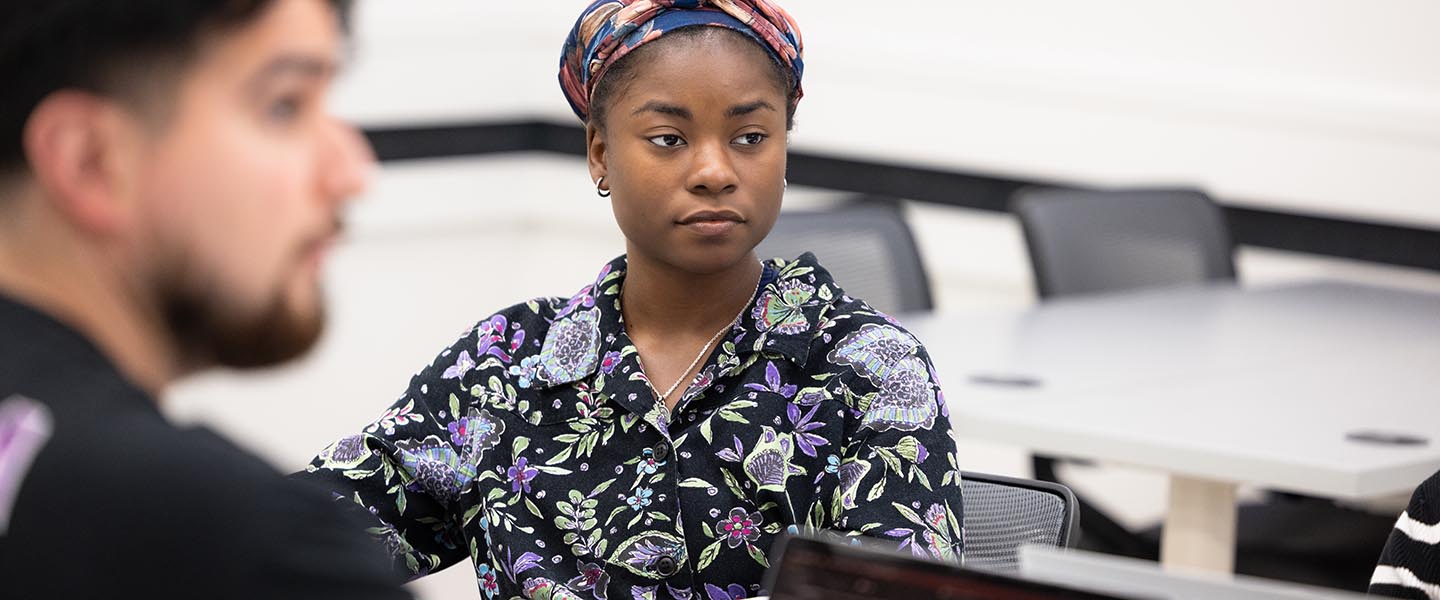 PNW student with a floral shirt listening to the professor 1440x600