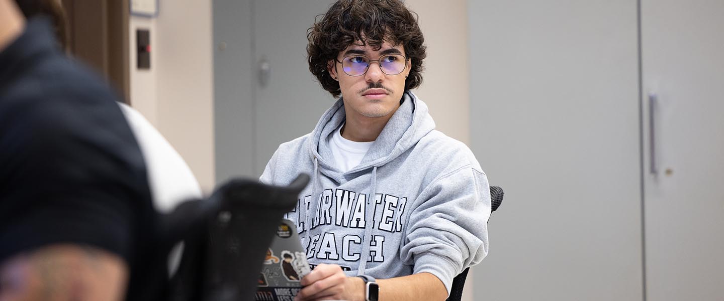 PNW student with a gray hoodie on looking at the professor while they are teaching 1440x600
