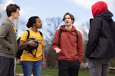 Four students stand together outside