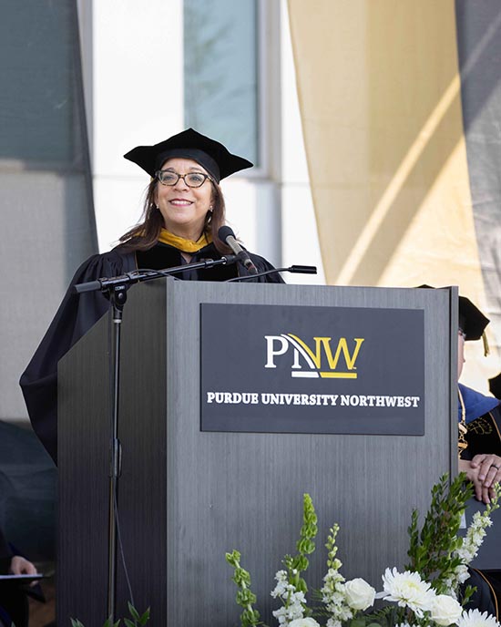 Alejandra Y. Castillo stands behind a branded podium.