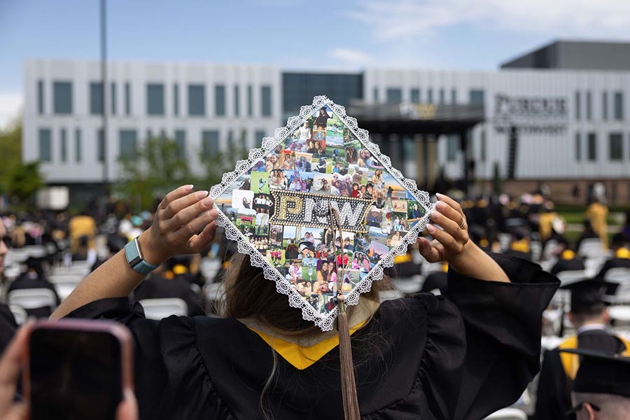A graduate displays a PNW cap decorated with photos
