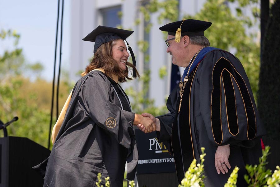 A graduate shakes hands with Chancellor Holford on stage