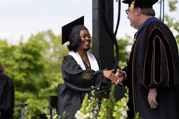 Chancellor Kenneth Holford shakes hands with a graduate.