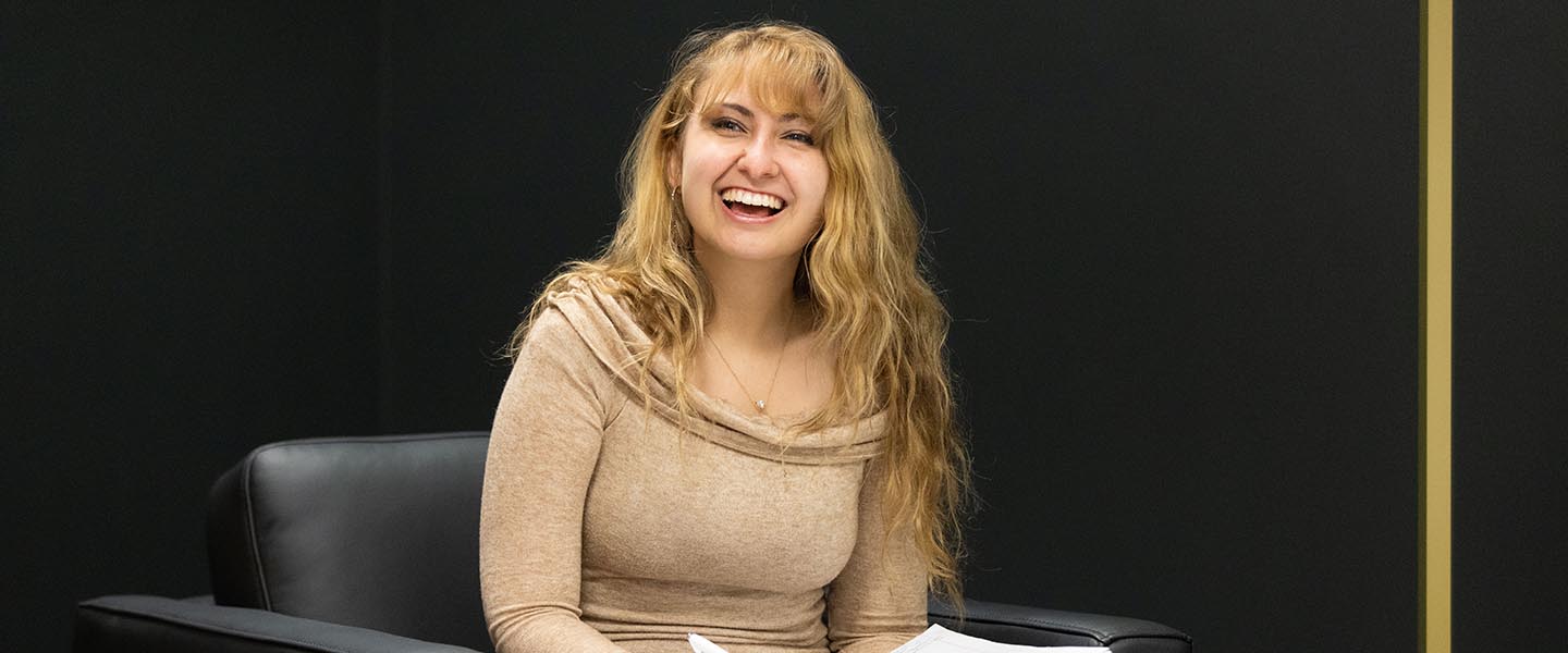 PNW student writing in a notebook while sitting in a chair 1440x600
