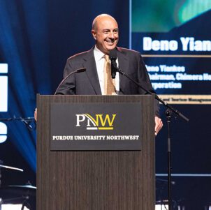 Deno Yiankes stands in front of a PNW branded podium.