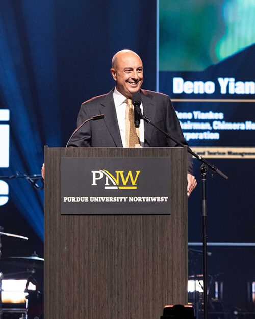 Deno Yiankes stands in front of a PNW branded podium.