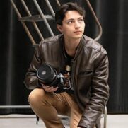 A PNW student in a leather jacket holds a DSLR camera.