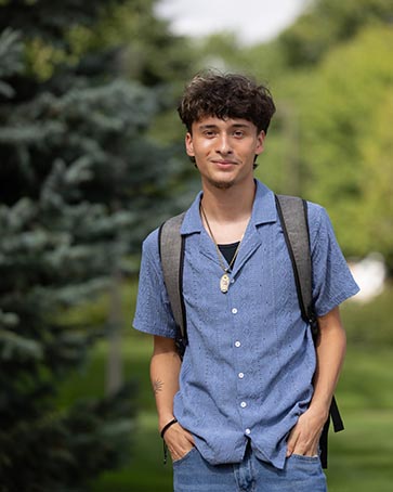 A PNW students stands with his hands in his pockets outdoors