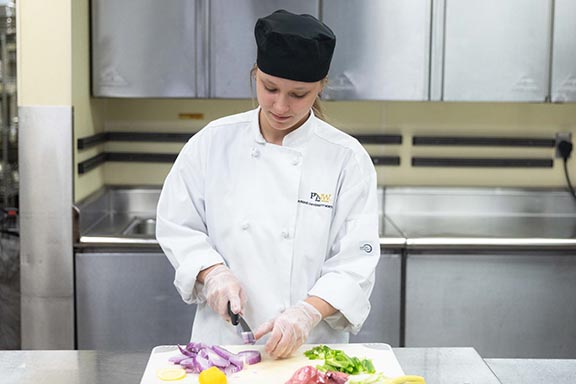 PNW student cutting up vegetables in the kitchen at the HTM building
