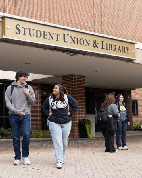 PNW students outdoors in front of the Student Union & Library building.