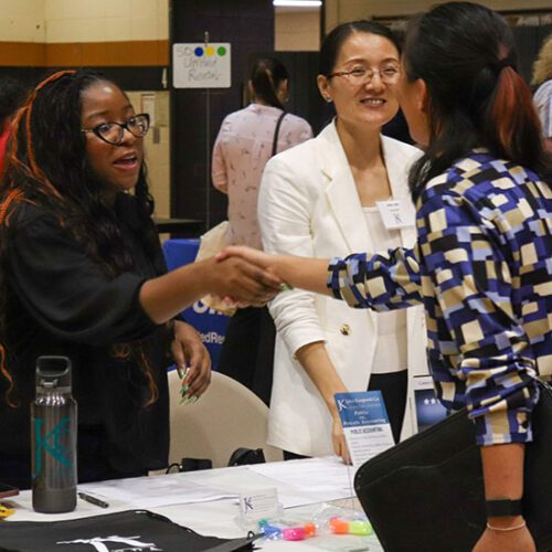 Three people talk during a career fair.