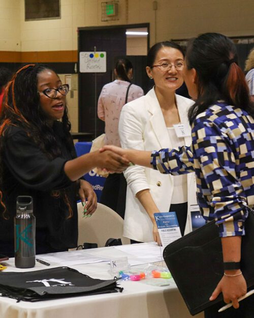 Three people talk during a career fair.
