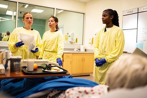 Three PNW Nursing students working with a mannequin in the Nursing Lab