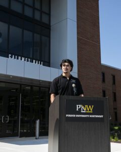 Adam Napravnik stands at a podium outside PNW's Calumet Hall.