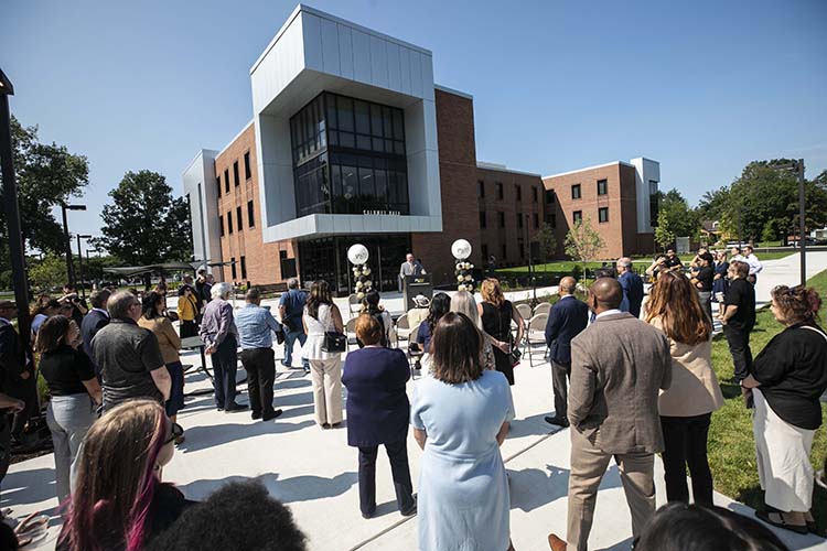 An audience gathers on the sidewalk in front of Calumet Hall during its ribbon-cutting ceremony.