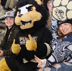 PNW mascot Leo sits with fans in the stands.
