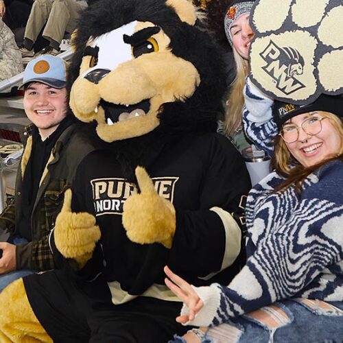 PNW mascot Leo sits with fans in the stands.