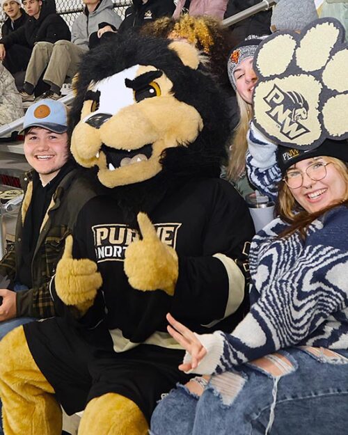 PNW mascot Leo sits with fans in the stands.