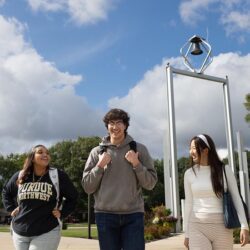 PNW students walk in front of the Bell Tower on campus.