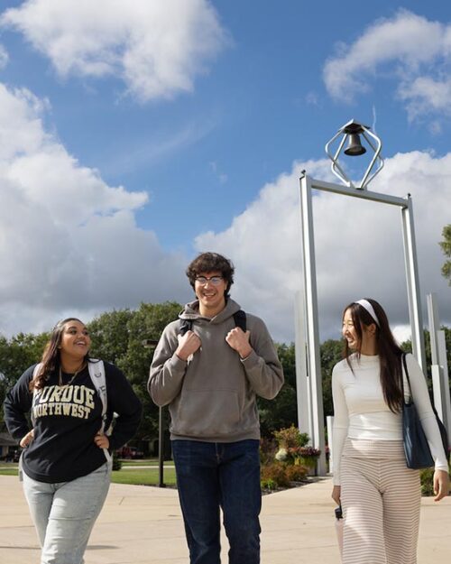 PNW students walk in front of the Bell Tower on campus.
