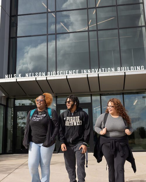 Three students walk together outside of the Nils Bioscience Building