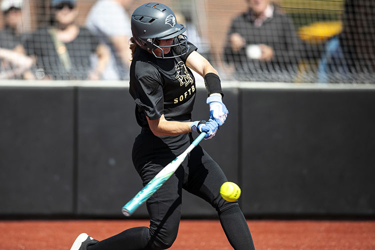 A PNW softball player hits a ball.