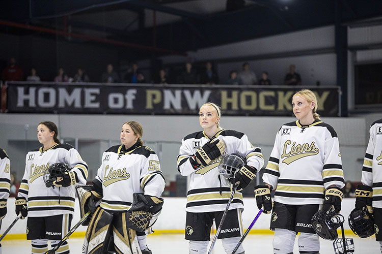 PNW women's hockey players stand during the national anthem.