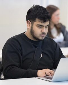 A student sits in class on a laptop